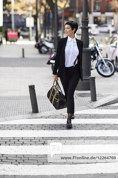 Lächelnde junge Geschäftsfrau überquert Straße