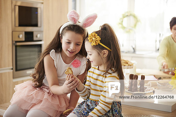 Zwei Mädchen  die sich in der Küche einen Keks ansehen.