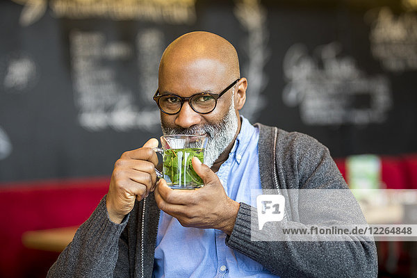 Porträt eines lächelnden Mannes mit einem Glas Tee im Café
