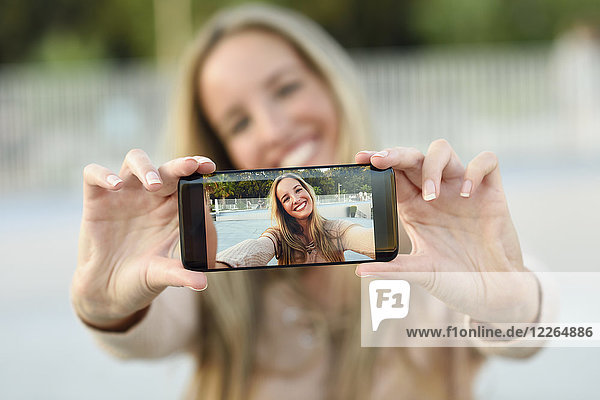 Happy young woman taking selfie with cell phone  close-up