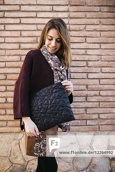 Fashionable woman with bag at brick wall
