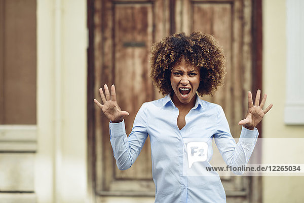 Porträt einer Frau mit Afro-Frisur im Freien schreiend