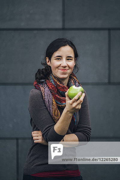 Portrait of smiling woman eating an apple