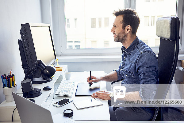 Smiling graphic designer working on computer at desk in office