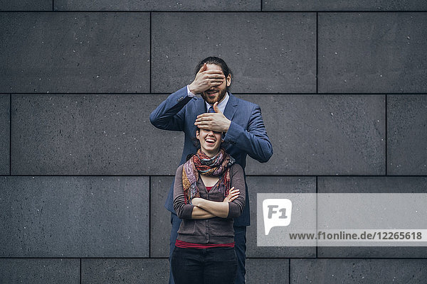 Businessman covering laughing woman's eyes