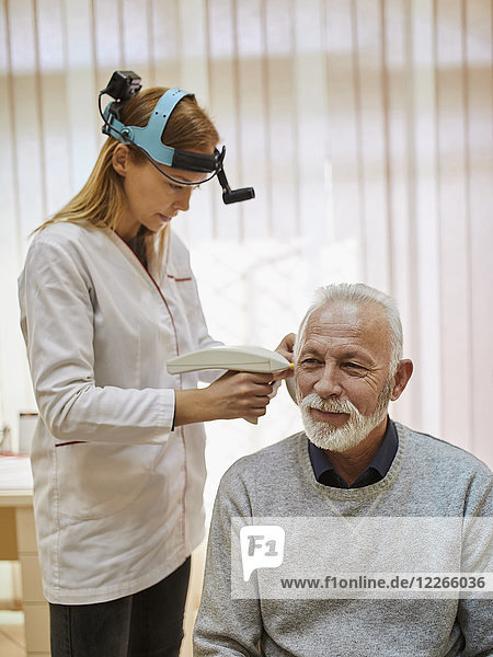 ENT physician examining ear of a senior man