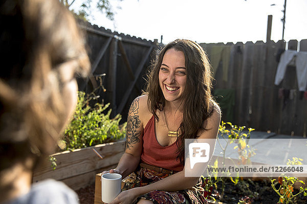 Zwei glückliche junge Frauen  die im Hinterhof reden.