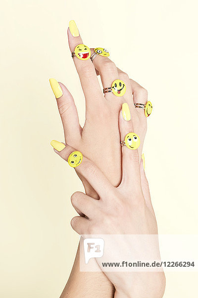 Nahaufnahme von Frauenhänden mit Emojis an Ringen