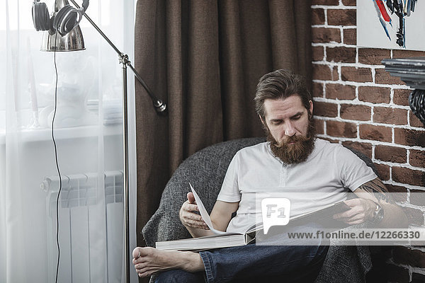 Man sitting on armchair looking at coffee-table book