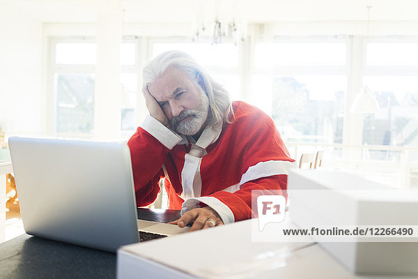 Frustrierte Weihnachtsmann mit Laptop zu Hause