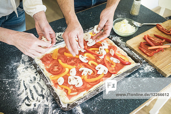 Nahaufnahme eines Paares bei der Zubereitung einer Pizza in der heimischen Küche