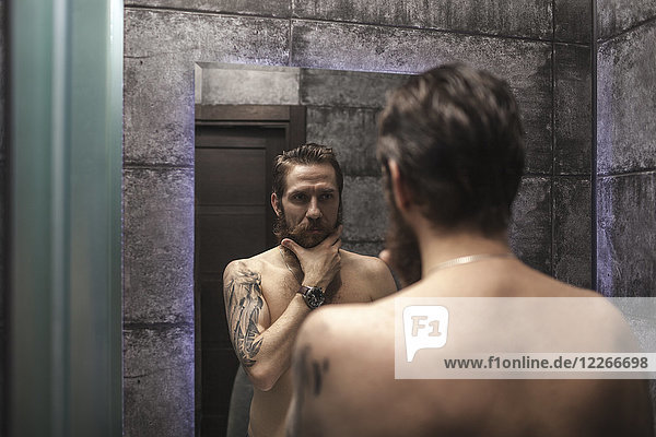 Portrait of bearded man looking at his mirror image