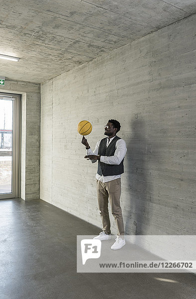 Geschäftsmann beim Balancieren von Basketball im Bürogeschoss