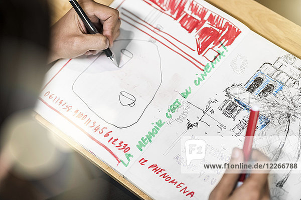 Künstler im Café sitzend  in sein Notizbuch zeichnend