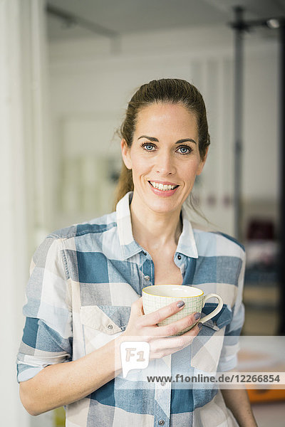 Porträt einer schönen Frau  die zu Hause Kaffee trinkt