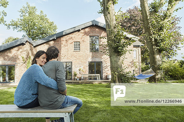 Smiling affectionate couple sitting in garden of their home