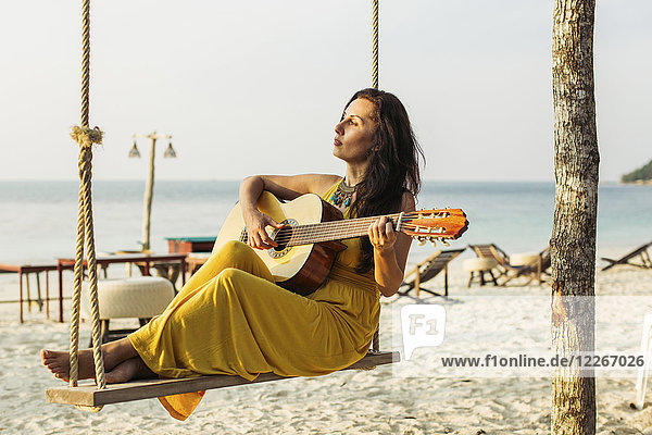 Thailand  Koh Phangan  Frau beim Gitarrespielen am Strand
