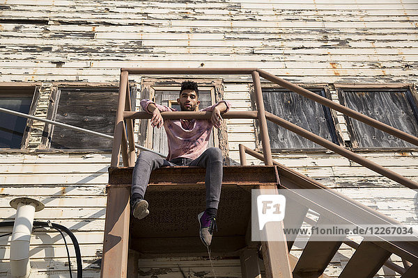 Portrait of stylish young man sitting on staircase outdoors