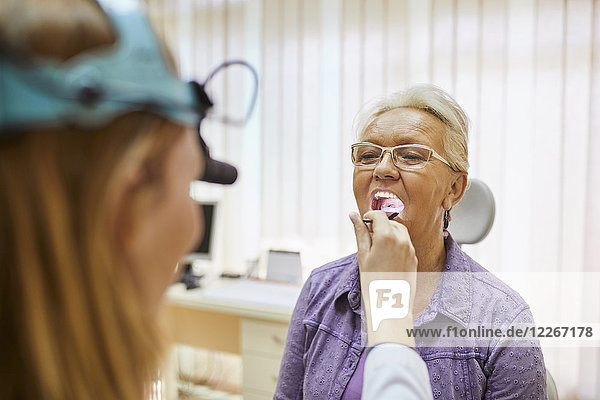 HNO-Arzt untersucht Mund einer älteren Frau