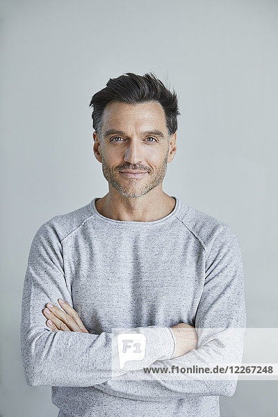 Porträt eines lächelnden Mannes mit Stoppel in grauem Sweatshirt