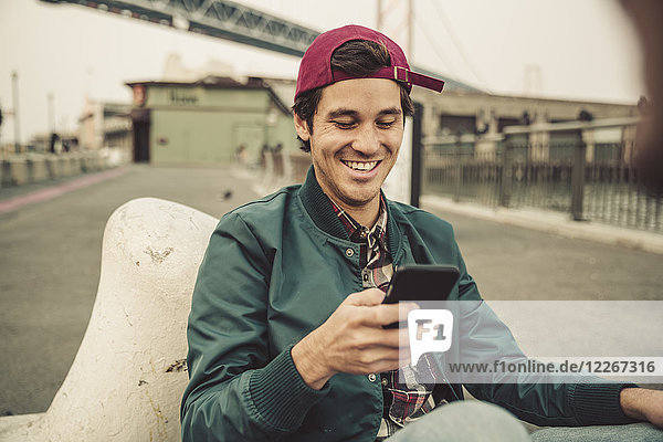 Porträt eines lächelnden jungen Mannes mit Handy