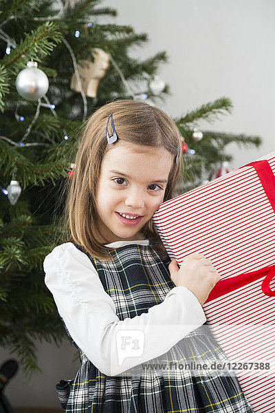 Porträt eines lächelnden kleinen Mädchens mit Weihnachtsgeschenk