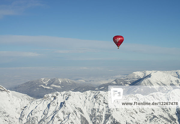 Österreich Salzkammergut Heißluftballon über alpiner Landschaft im Winter