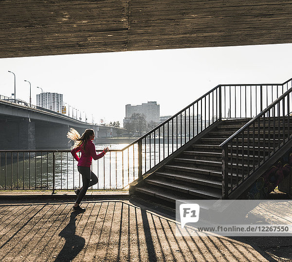 Junge Frau rennt zur Treppe an einem Fluss.