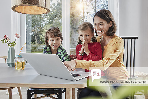 Glückliche Mutter mit zwei Kindern mit Laptop zu Hause