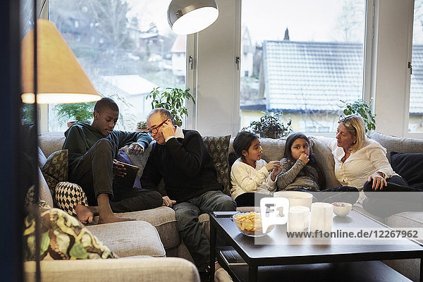 Mehrgenerationen-Familie sitzt zu Hause auf dem Sofa
