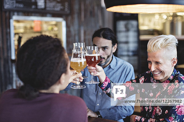 Multi-ethnic friends toasting glasses while sitting at bar
