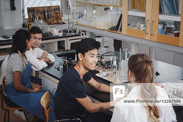 Hochwinkelansicht von multiethnischen jungen Universitätsstudenten  die auf Stühlen im Chemielabor sitzen.