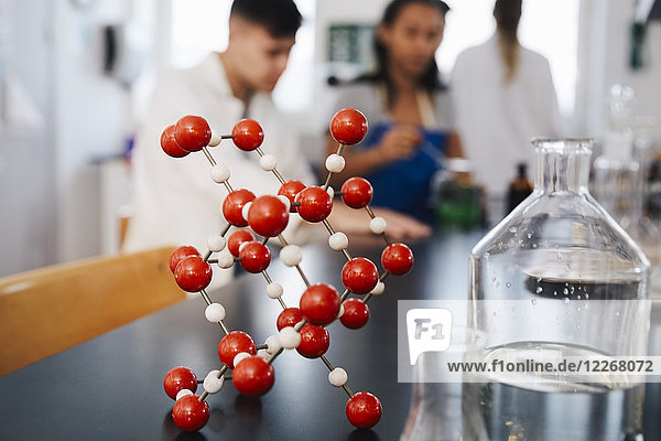 Molekülstruktur durch Glaswaren auf dem Tisch gegen junge Studenten im Chemielabor
