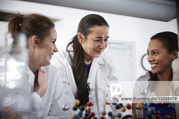 Lächelnde reife Chemielehrerin mit jungen Studentinnen im Klassenzimmer der Universität