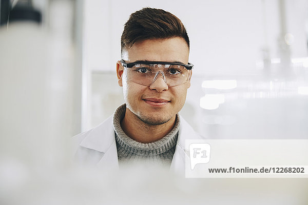 Portrait of confident young chemistry student wearing eyewear in laboratory
