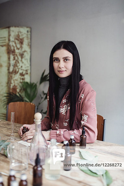 Porträt einer selbstbewussten Unternehmerin bei der Zubereitung von Parfüm am Tisch in der Werkstatt