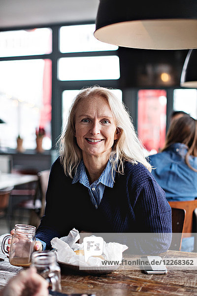 Porträt einer lächelnden reifen Frau am Esstisch im Restaurant