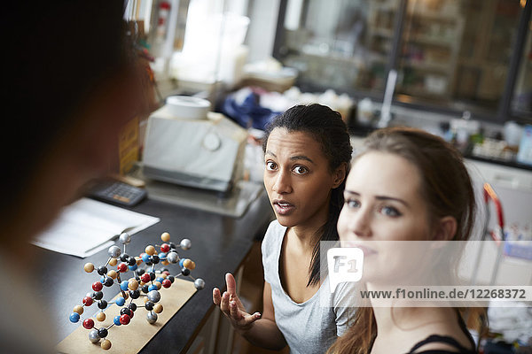 Junge Studentinnen nach Molekülstruktur mit Blick auf die reife Lehrerin im Chemieunterricht