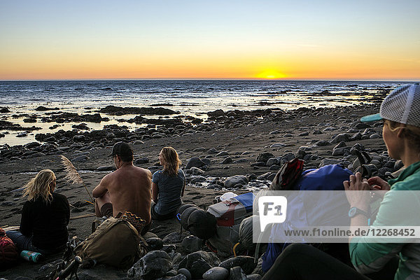 Wanderer ruhen sich bei Sonnenuntergang am Strand aus  während sie auf dem Lost Coast Trail wandern  Kings Range National Conservation Area  Kalifornien  USA