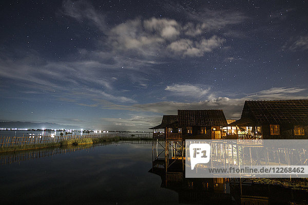 Himmel und Wolken über beleuchteten Stelzenhäusern am Inle-See bei Nacht  Shan-Staat  Myanmar