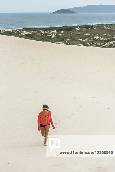 Junge Frau läuft in den Sanddünen von Joaquina  Florianopolis  Santa Catarina  Brasilien