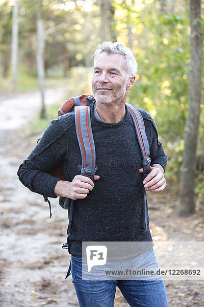 Gray-haired man smiling while hiking in forest with backpack  Massachusetts  USA