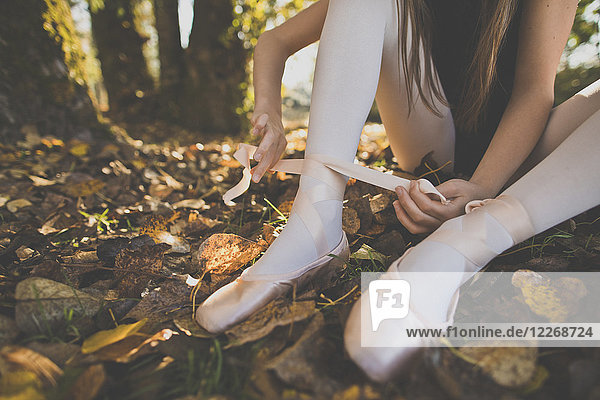 Young girl ties up ballet shoes in outdoor setting  British Columbia  Canada