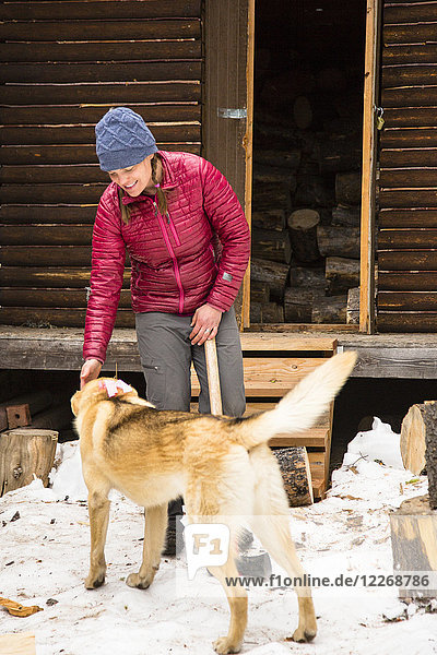 Frau beim Holzhacken mit Hund