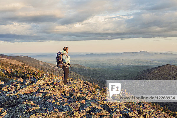 Female hiker standing and admiring landscape from top of Mount Abraham at dusk  Maine  USA