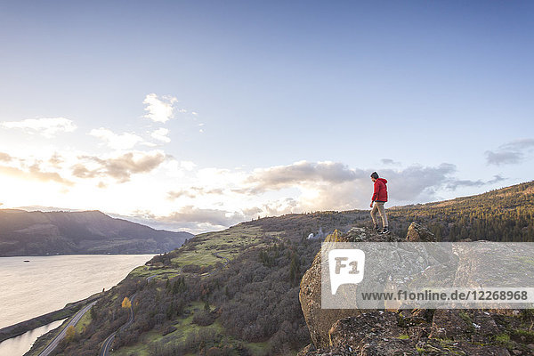 Männlicher Wanderer  der am Rande einer Klippe steht und auf den Fluss und die Landschaft darunter hinunterblickt  Lyle  Oregon  USA