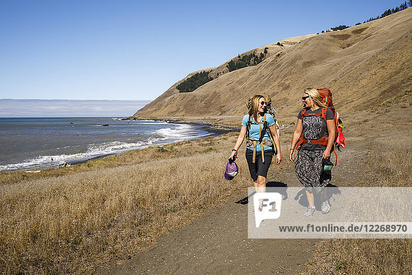 Two female backpackers hiking along beach and talking  Lost Coast Trail  Kings Range National Conservation Area  California  USA