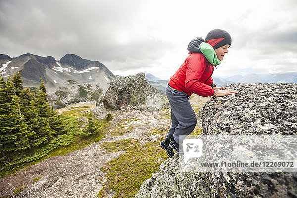 Young boy scrambling up rocky ridge  Merritt  British Columbia  Canada