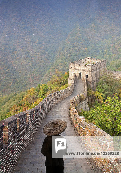Rückansicht eines Mannes mit traditionellem Strohhut auf der Großen Mauer von China.
