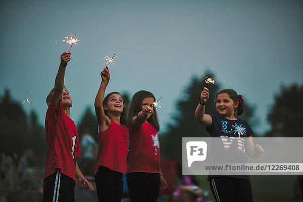 Group of friends  arms raised holding sparklers